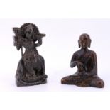 A carved soapstone figure depicting Krishna playing the flute together with a cast brass Buddha,
