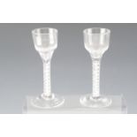 A pair of mid 18th Century wine glasses having opaque gauze spiral and thread ribbon twist stems,
