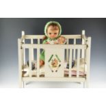 A vintage doll's cot together with two composition dolls, the larger having articulated joints and