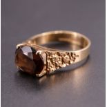 A 1970s smoky quartz and 9 ct gold ring, having an oval 10 x 8 mm stone, set on a plain four prong