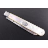 An Edwardian silver and mother of pearl folding fruit knife, having plain grips, one side with an