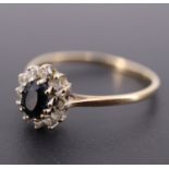 A sapphire, white paste and 9 ct gold flowerhead cluster ring, the oval sapphire of approx 0.3 ct,