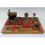 A group of Mamod workshop tools, machines and a steam engine, affixed to a wooden base, base 30.5