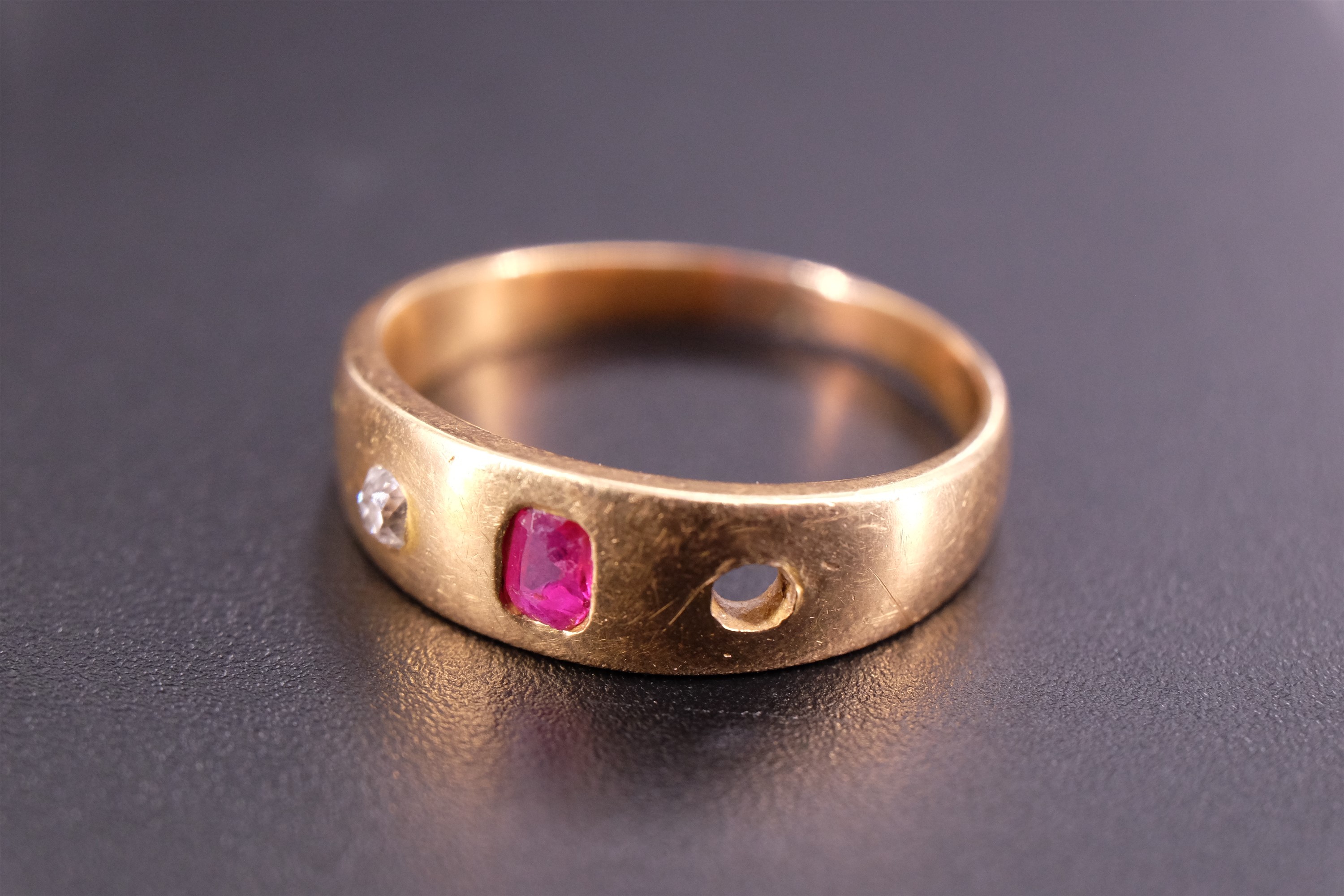 An 18 ct yellow metal, diamond and pink stone finger ring, the stones sunken set on a broad tapering