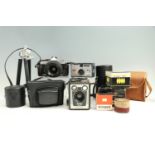 An Olympus OM-2 camera, Brownie model E, Instamatic 50 camera, Cosmic Symbol, two camera tripods,