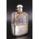 An Edwardian silver-mounted cut glass hip flask, having an oblate hinged cap closing by means of a
