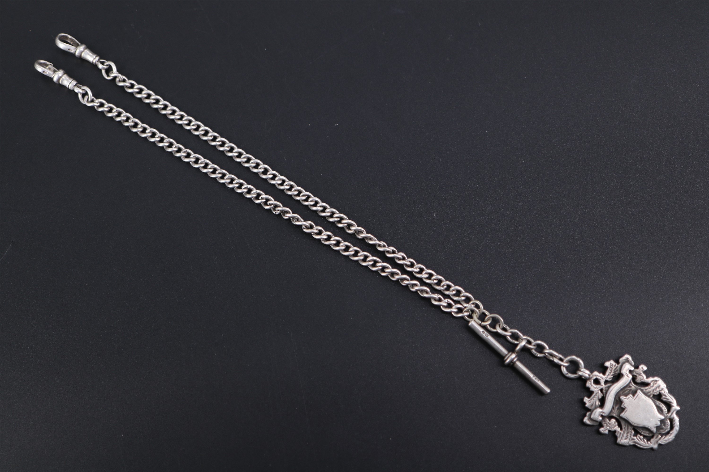 An Edwardian silver curb link double Albert watch chain with shield shaped fob medallion, 39 cm,