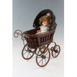 A Victorian doll's pram together with an early 20th Century composition doll having sleeping eyes,