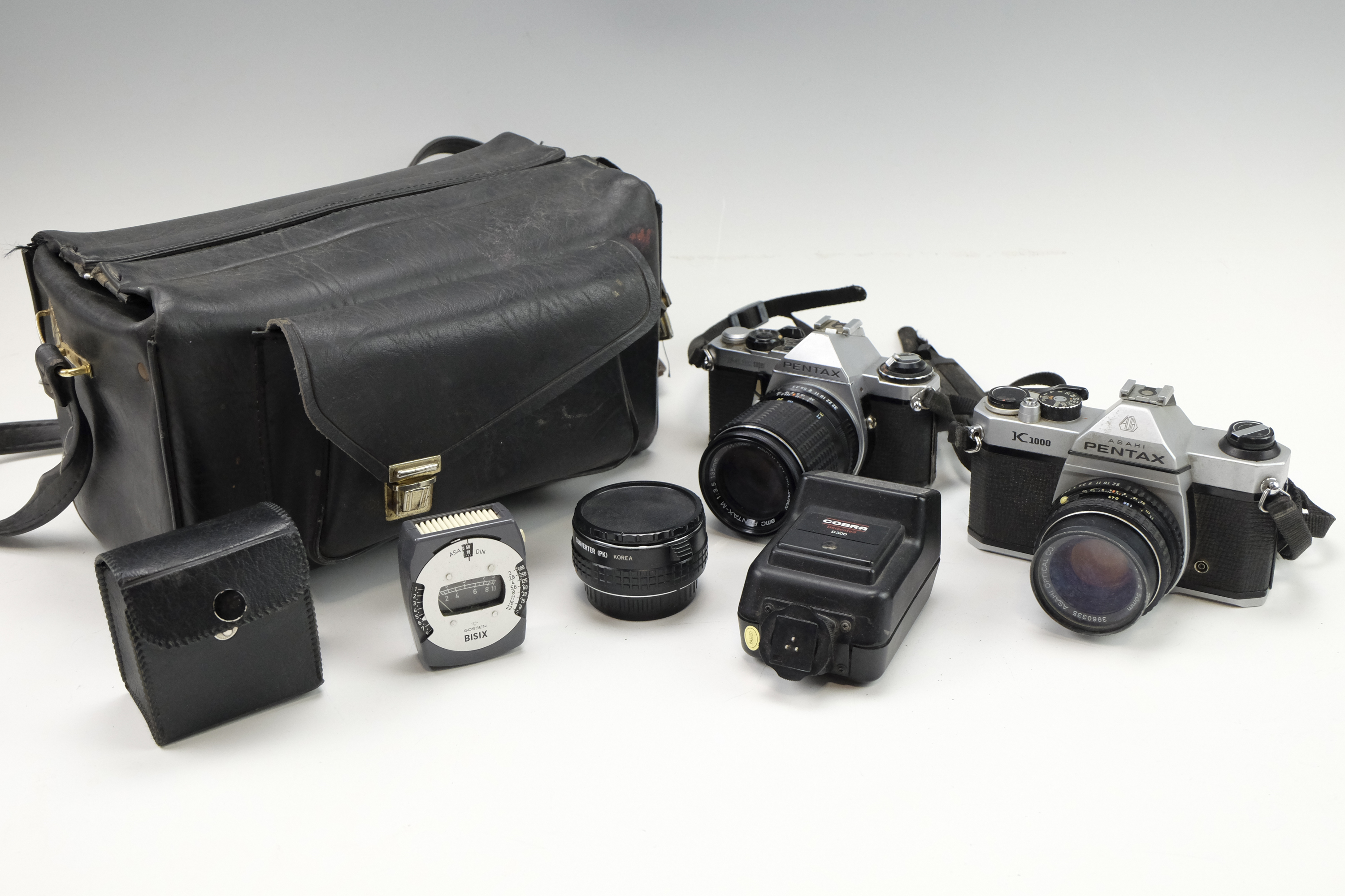 A Pentax K1000 film camera body together with a Pentax MEsuper, two Asahi Optical Co. lenses, a