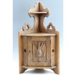A late 19th Century carved oak corner cabinet decorated with Gothic trefoil and relief carved game