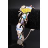 A vintage silver / white metal charm bracelet containing a large number of regional enamelled and