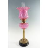 A Victorian columnar brass and cranberry glass oil lamp, having a duplex coronet burner, 61 cm to