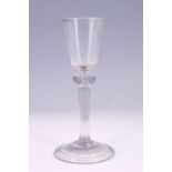 A mid-18th Century gin or wine glass, having a pointed round funnel bowl and basal knop with tear,