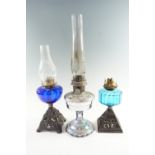 Two early 20th Century cast iron and blue glass oil lamps, both having single wick prong burners,