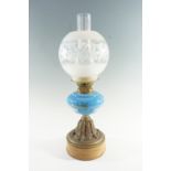 An early 20th Century brass and blue glass oil lamp, having a floral decorated glass font on an