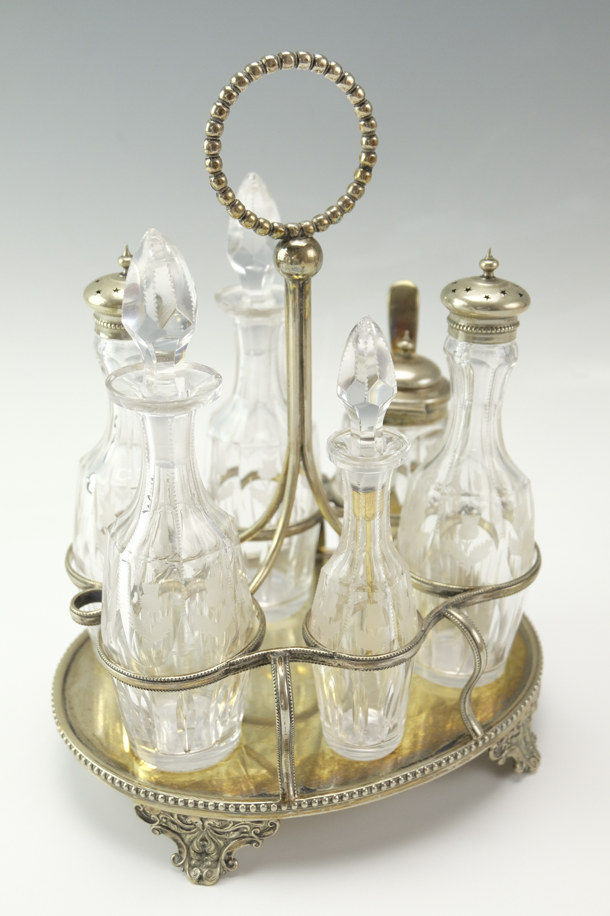 A late 19th / early 20th Century condiment set, the glass cruets being wheel-cut in depiction of