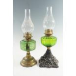 Two early 20th Century emerald glass oil lamps, respectively having cast iron and spun brass