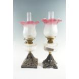 Two 19th Century and later cast iron and amethyst glass oil lamps, both having duplex coronet