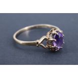 A 1980s amethyst finger ring, having a 7 x 5 mm oval stone claw set on an open gallery of