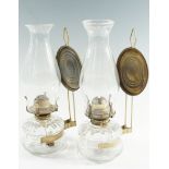 A pair of early 20th Century German glass oil lamps, each having a brass clip-on wall bracket with a