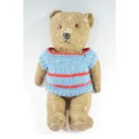 An early 20th Century teddy bear with glass eyes and hand knitted jumper, 39 cm