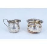 A late Victorian silver sugar bowl and cream jug, of ovoid form having everted and gadrooned rims,