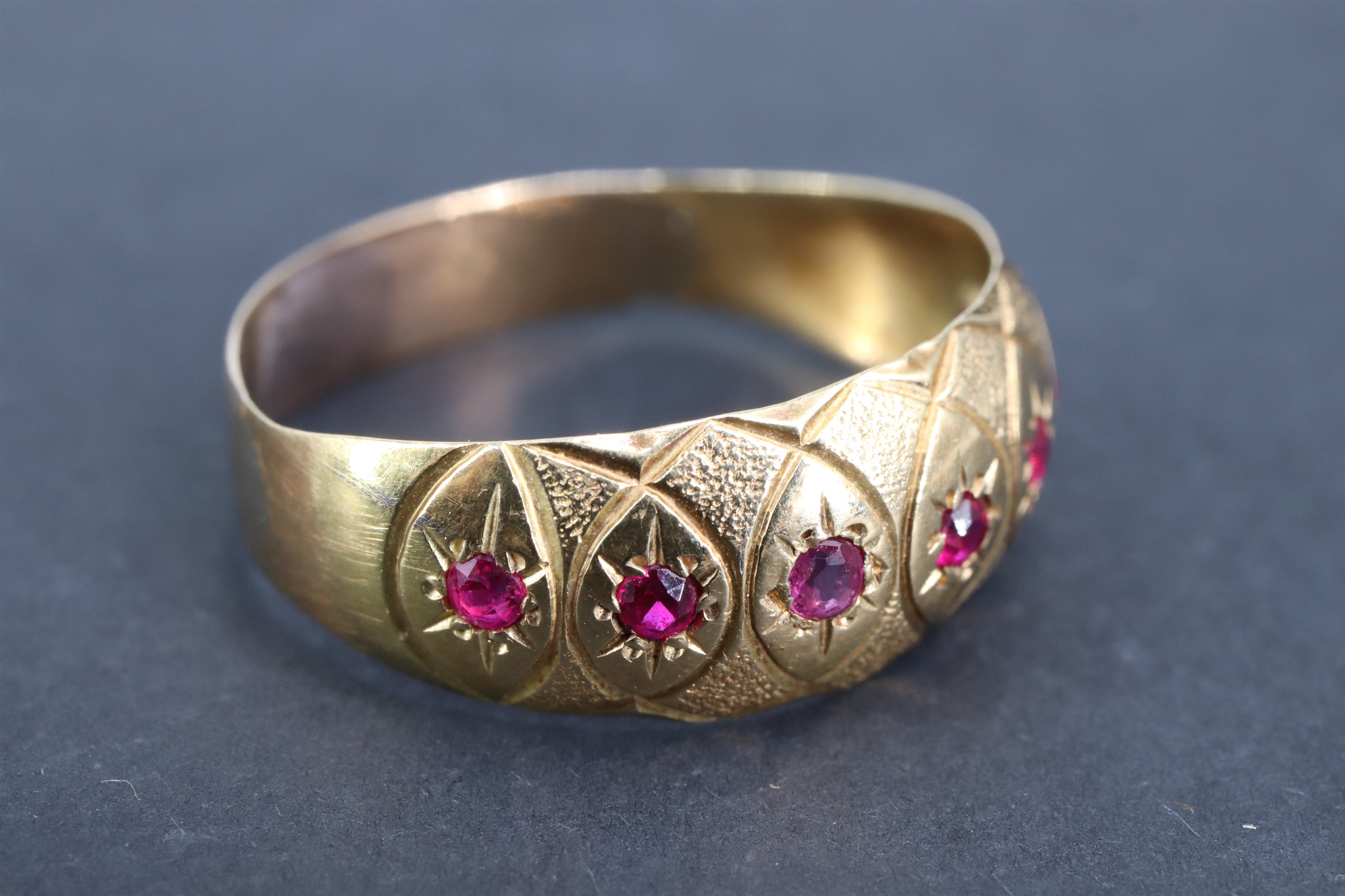 A vintage ruby and yellow metal finger ring, the convex adorsed tapering band gypsy-set with a