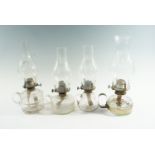 Four late 19th / early 20th Century glass finger lamps, having single wick prong burners, tallest