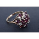 An ruby and diamond cluster dress ring, having a central 3.5 mm brilliant ruby, above and surrounded