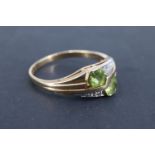 An unusual peridot and diamond 9 ct gold finger ring, having two offset 4 mm hexagonal peridots,
