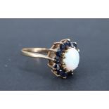 An opal and blue sapphire finger ring, the 8 x 6 mm opal cabochon set above 12 surrounding