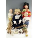 A large vintage bisque-headed doll together with a group of composition dolls and a wooden puppet,