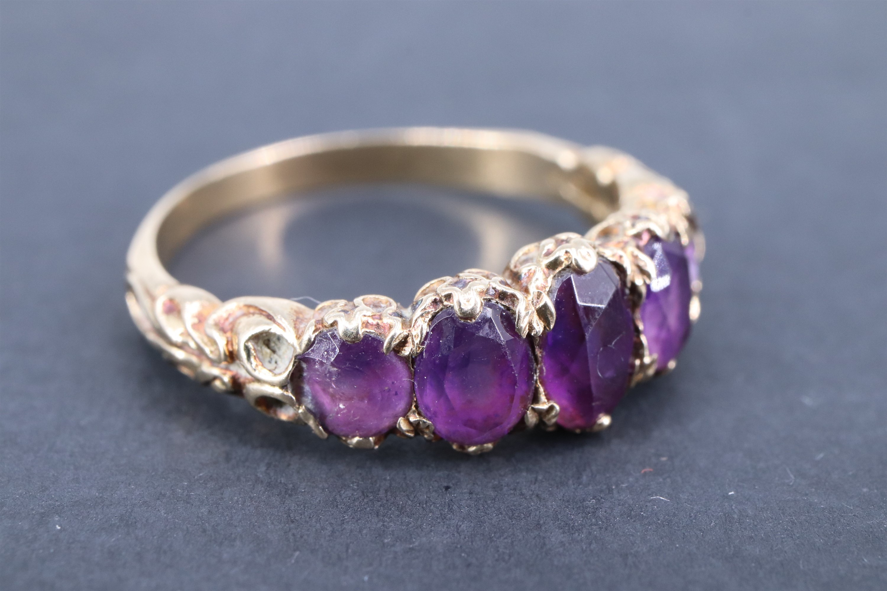 A vintage amethyst finger ring, having five adorsed graduated oval stones, the stiff-leaf