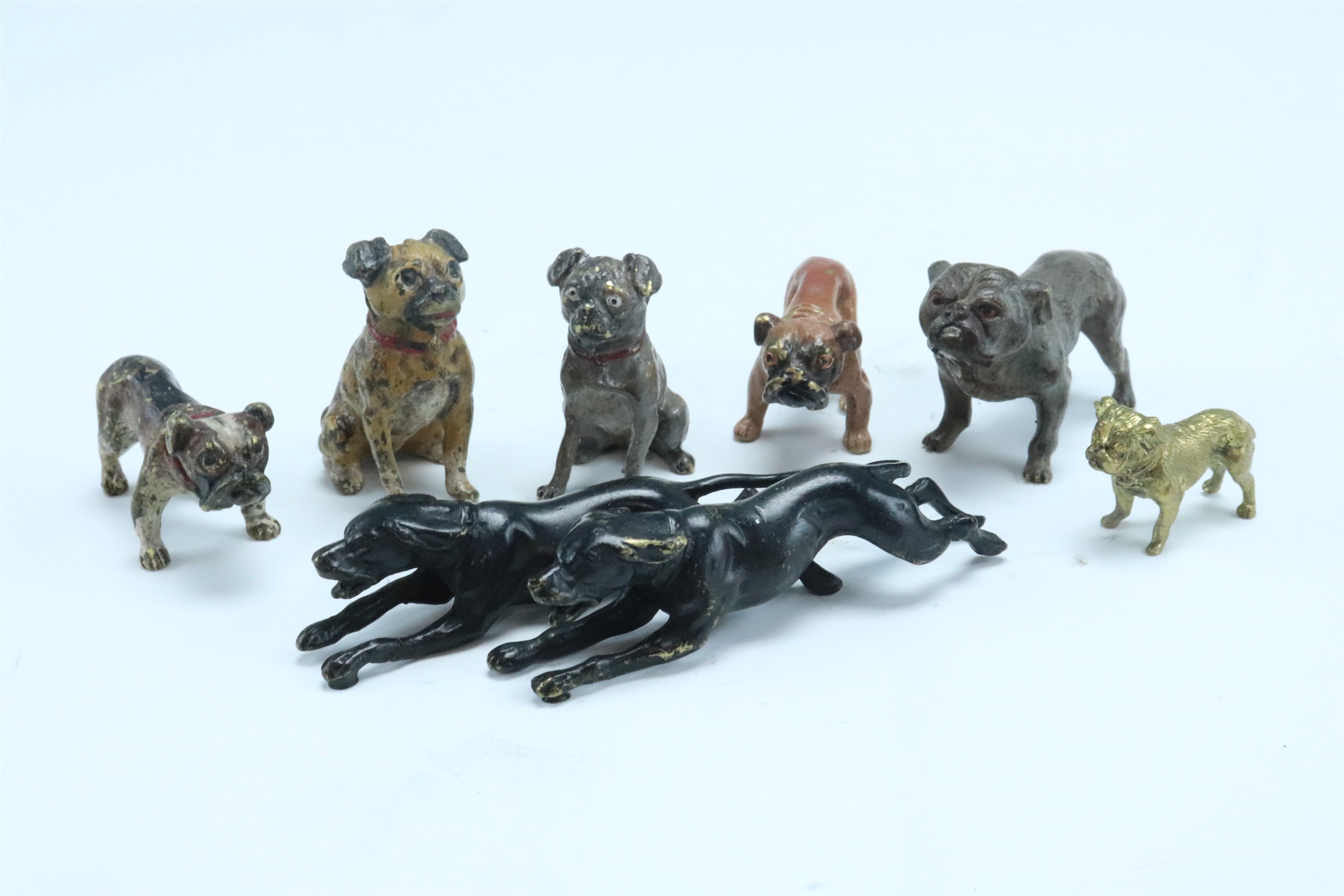 Five cold painted bronze figures of pug dogs, together with a cast brass example, and a pair of