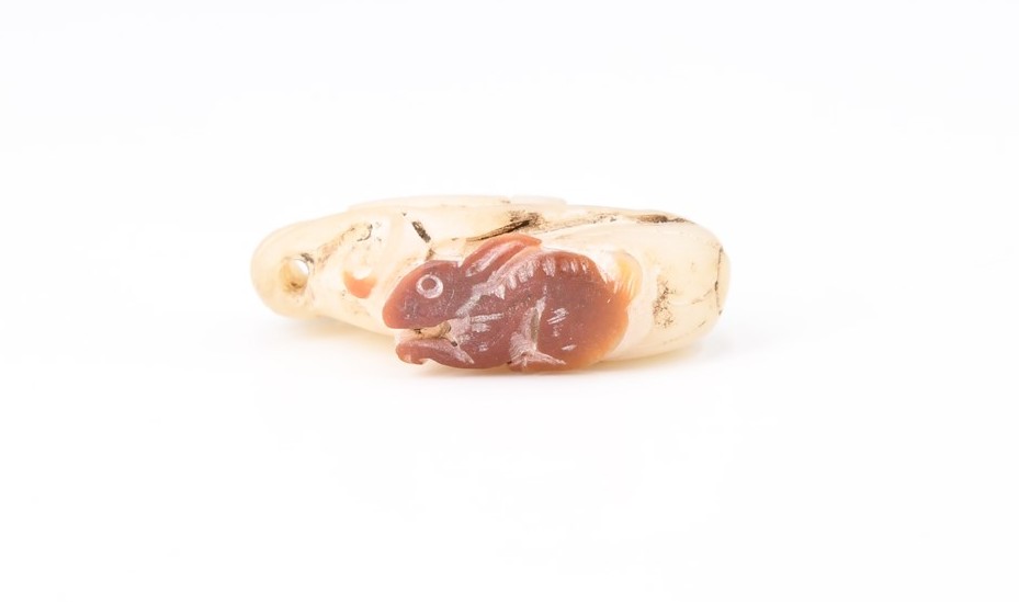 A Chinese carved jade pendant or toggle in the form of a rabbit and vine fruit, 33 mm