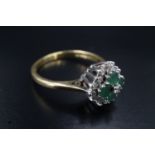 An emerald and diamond dress ring, having a square of four 3 mm emeralds, centred with an eight-