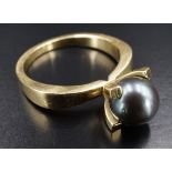 A modernist "pewter" pearl ring, the 7 mm pearl cradled by four tapering square-section claws on a