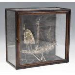 An early 20th Century white and base metal model fighting junk, in glazed hardwood display case,