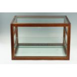 A vintage glass and mahogany counter top display, having a subtly sloping front and shelves, 31 cm x