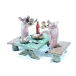 A cold painted bronze figure of two pigs at a picnic table quaffing wine, impressed mark to base,