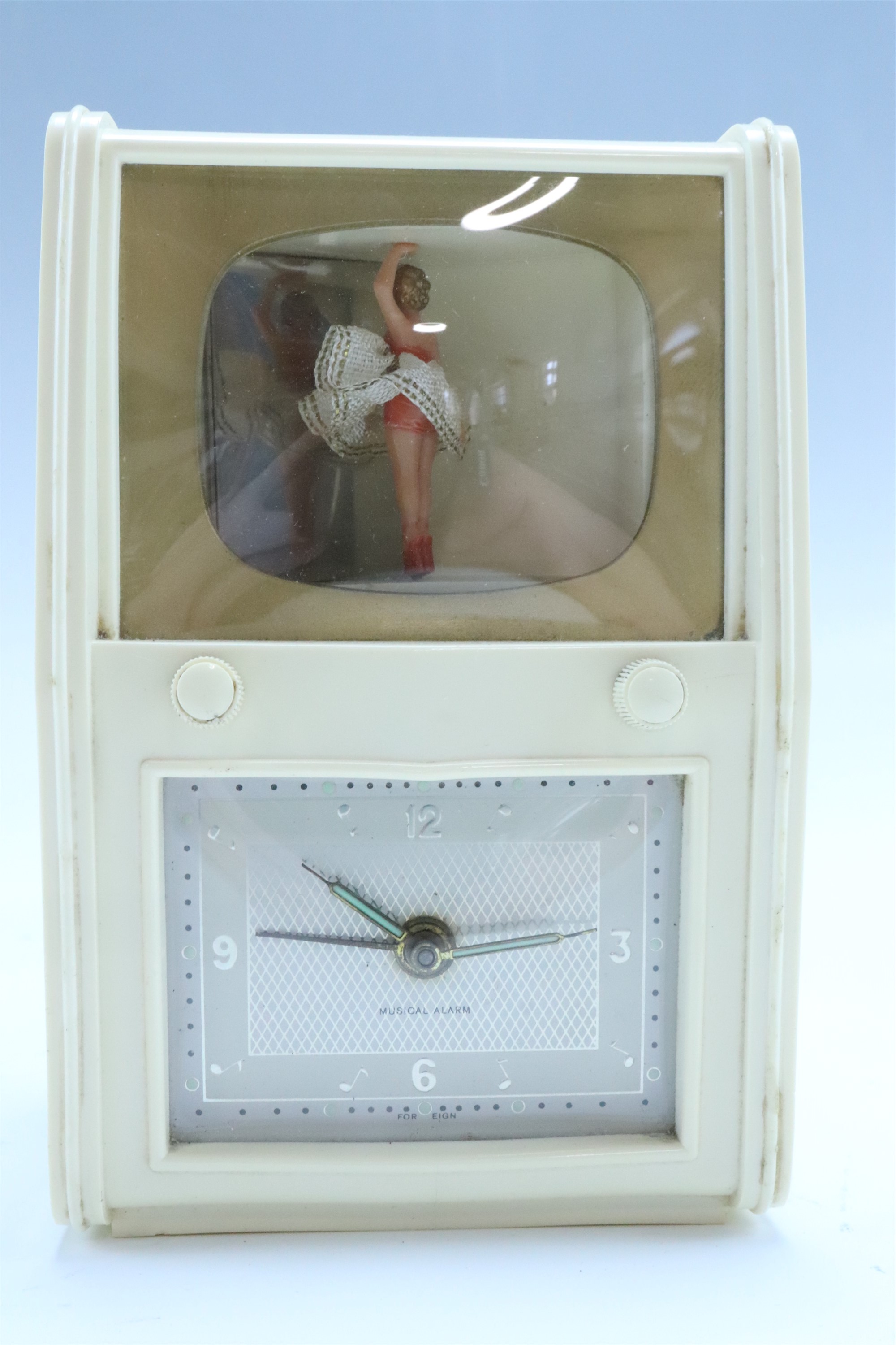 A German kitsch automaton musical alarm clock, having an ivory coloured composition case modelled as