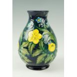 A late 20th Century Moorcroft Buttercup pattern vase, blue body, base signed impressed marks to