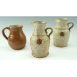 A pair of 20th Century studio pottery stoneware jugs, each bearing an applied stylized seal to the
