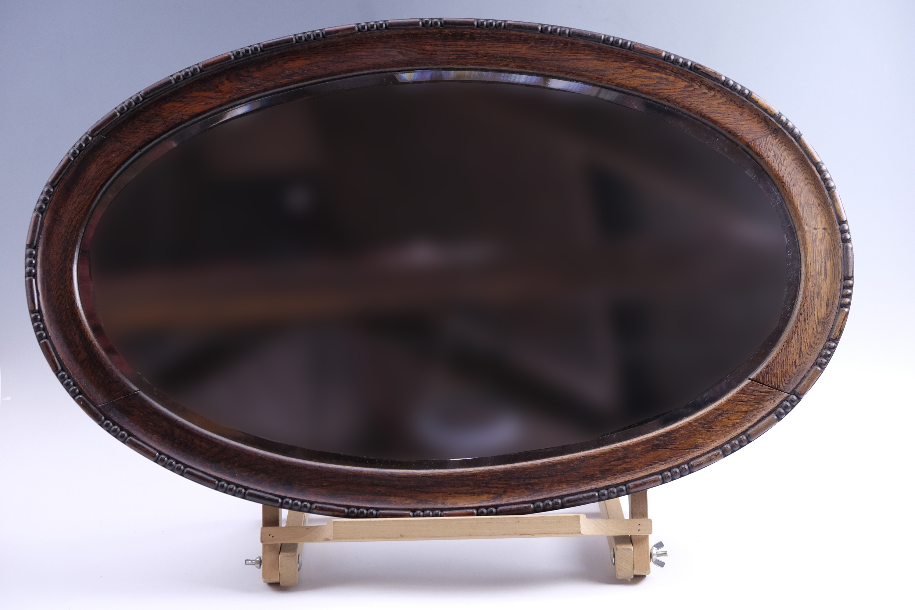 An oval George V oak framed bevelled glass mirror, 77 x 47.5 cm