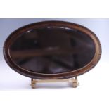 An oval George V oak framed bevelled glass mirror, 77 x 47.5 cm