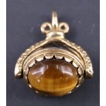 An almandine and tiger's eye 9 ct gold revolving fob, of oblate spheroid shape having adorsed