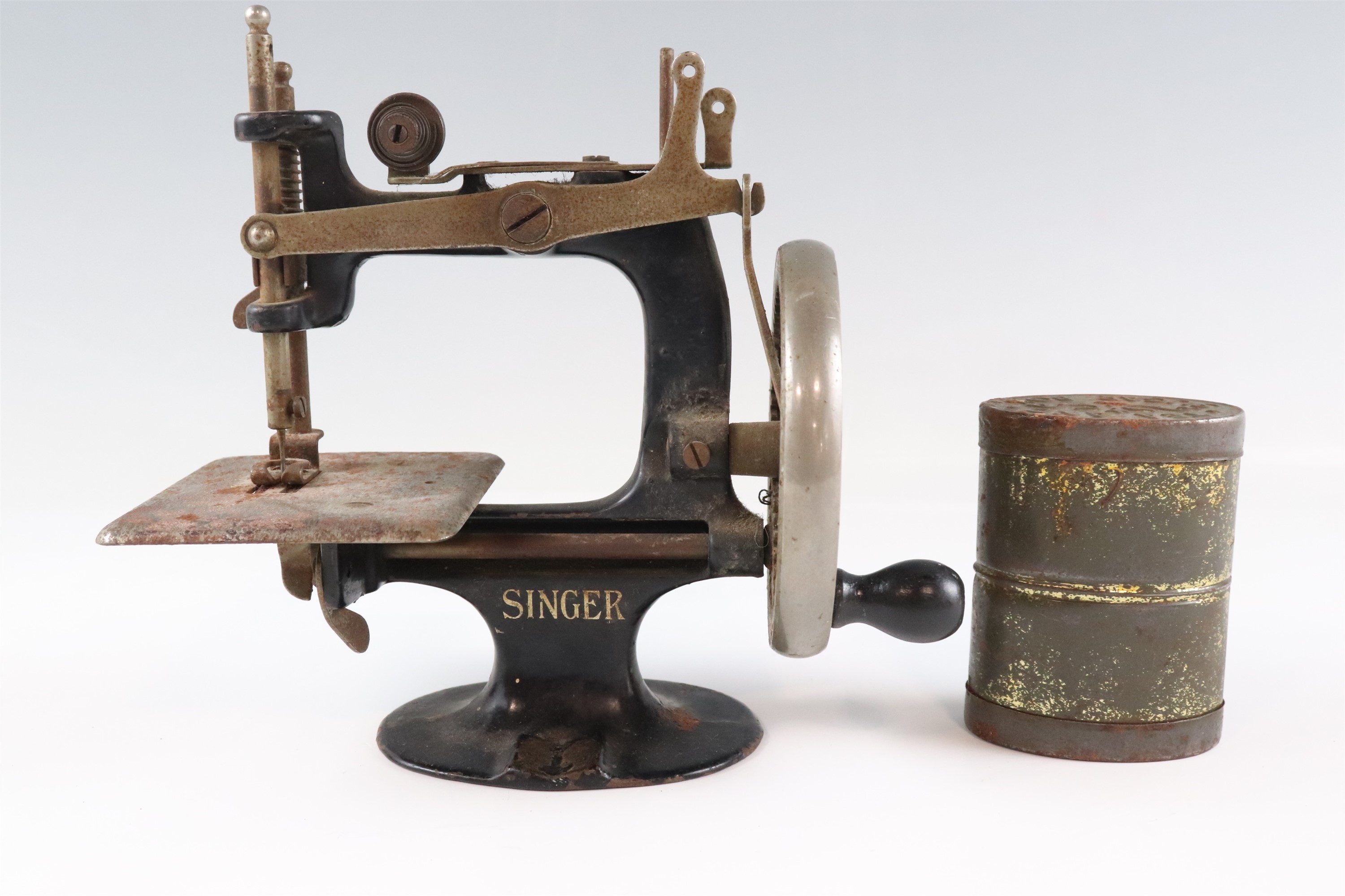 An early 20th Century toy hand-cranked Singer sewing machine together with an embossed double