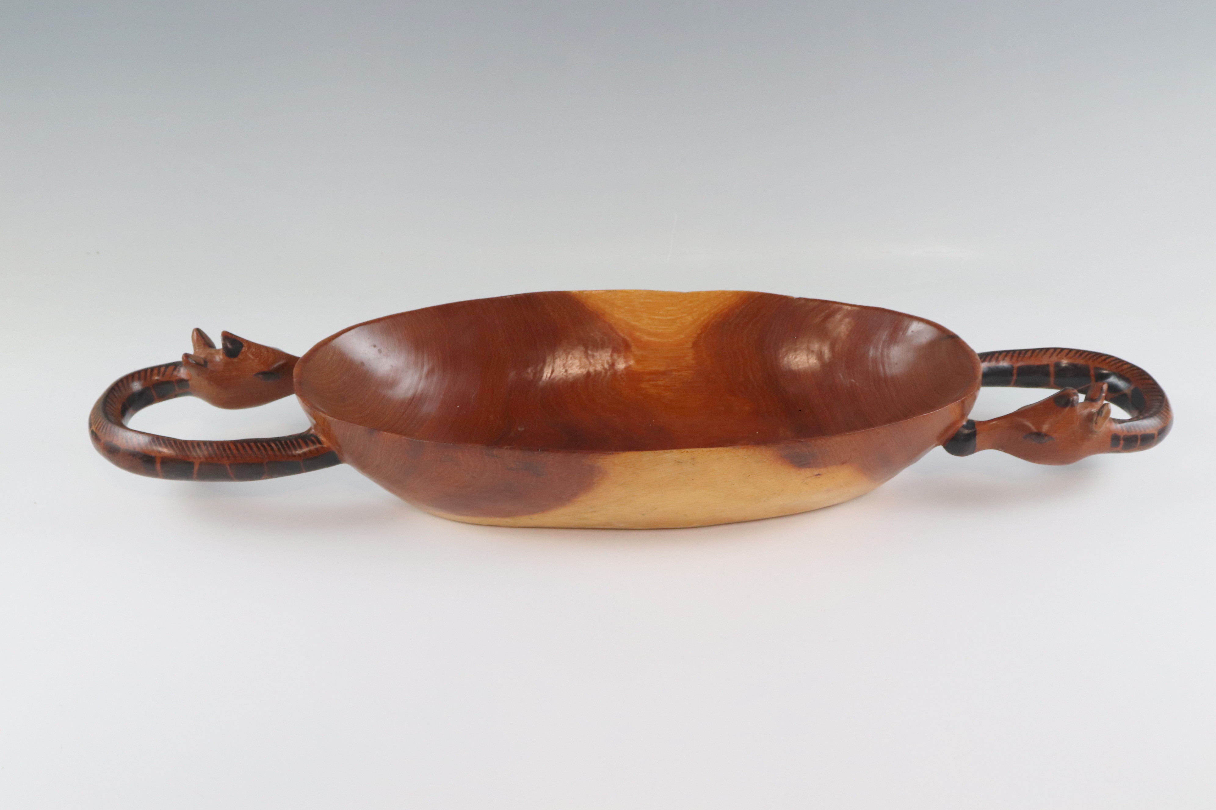 A large African carved and painted wooden bowl, its handles modelled as giraffes heads, 60 cm