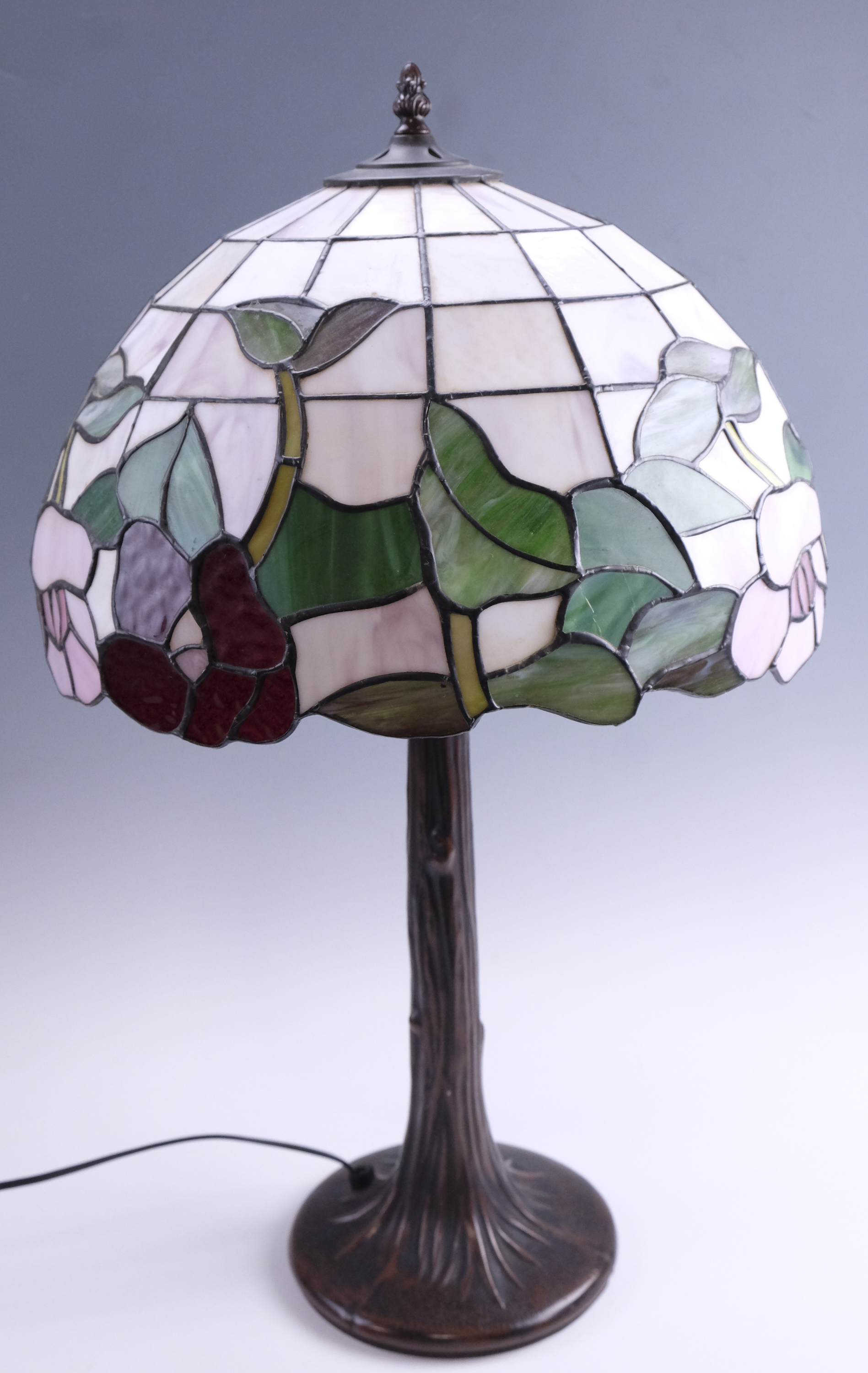 A late 20th Century Tiffany style table lamp, having a leaded glass shade on a patinated