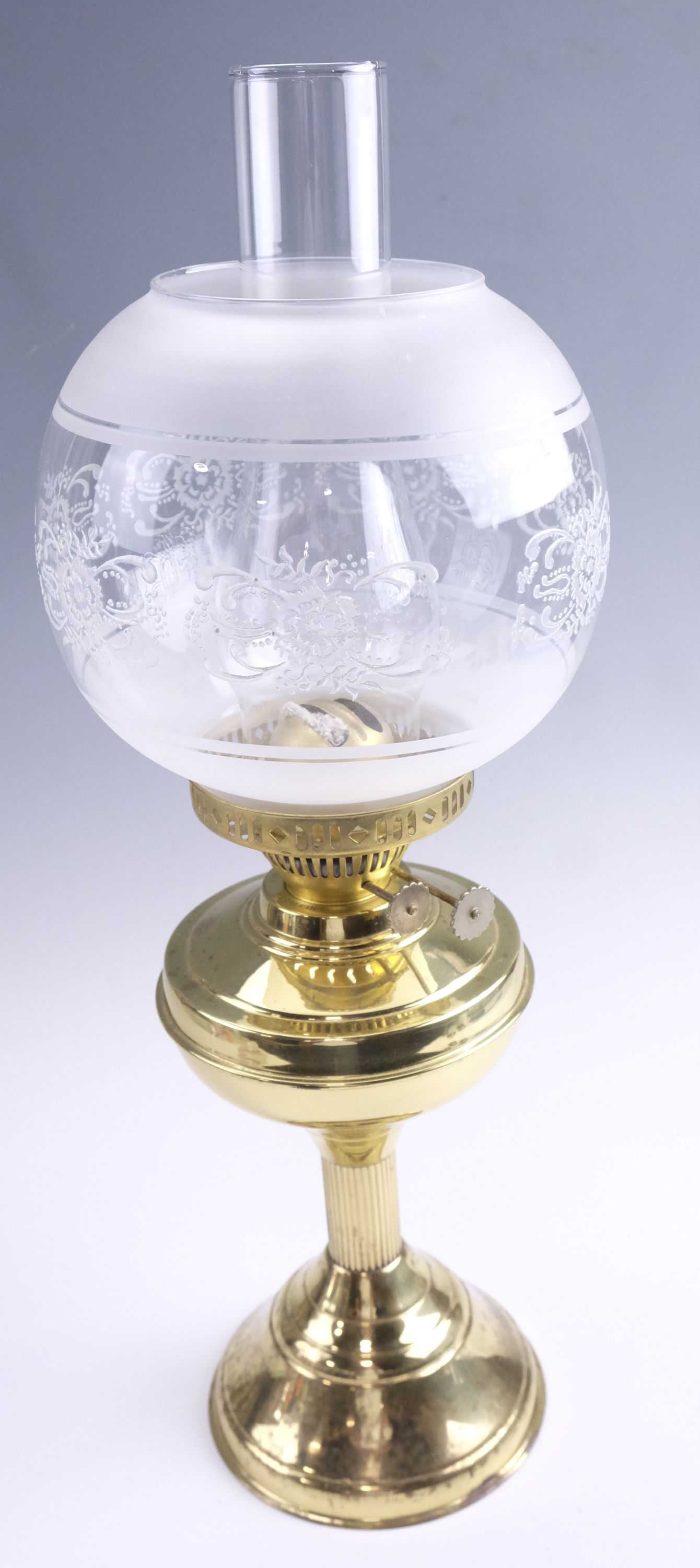 A late 20th Century brass twin wick oil lamp, having a frosted and floral decorated glass globe,
